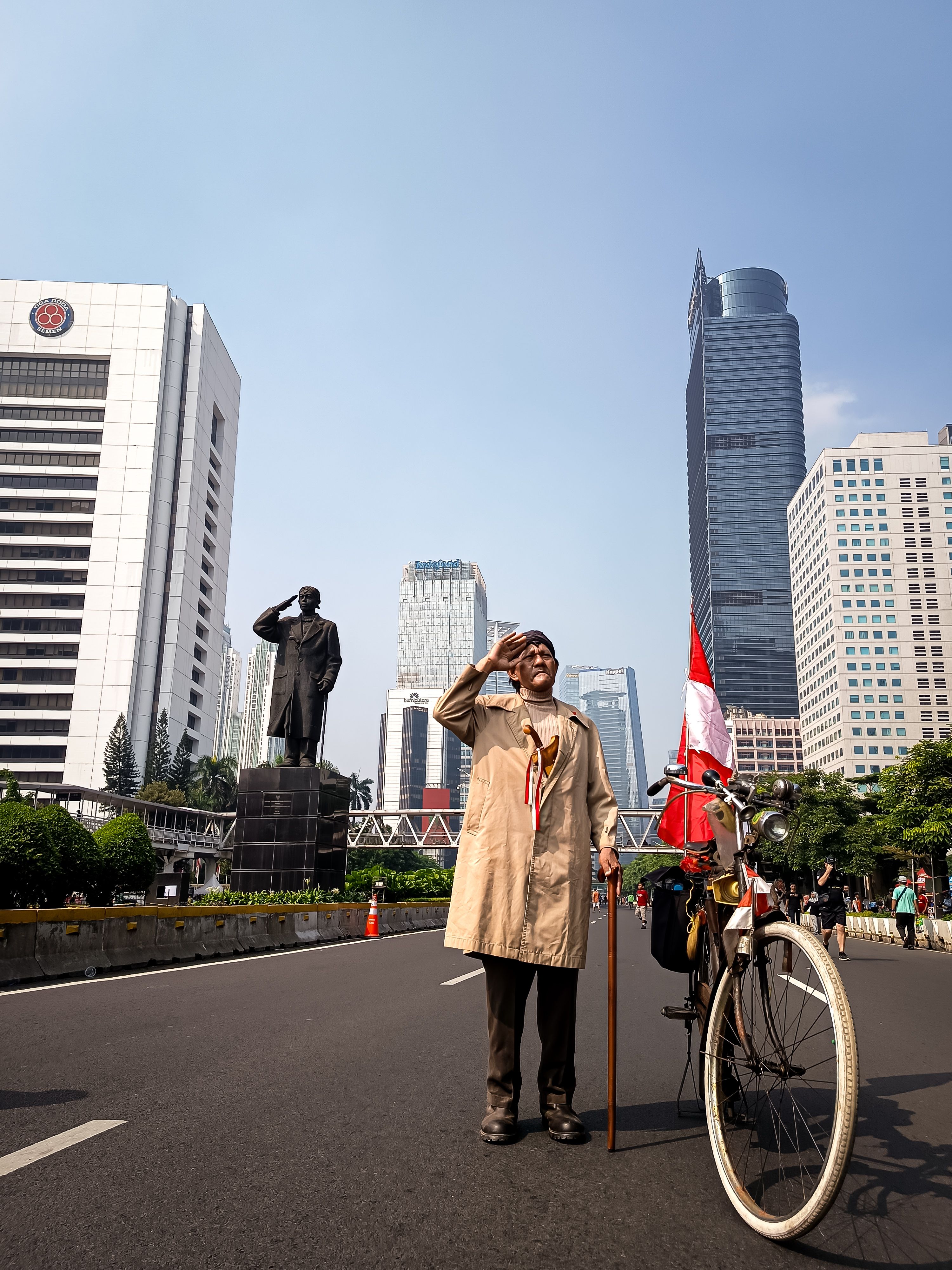 Elderly man saluting with bicycle in Jakarta street