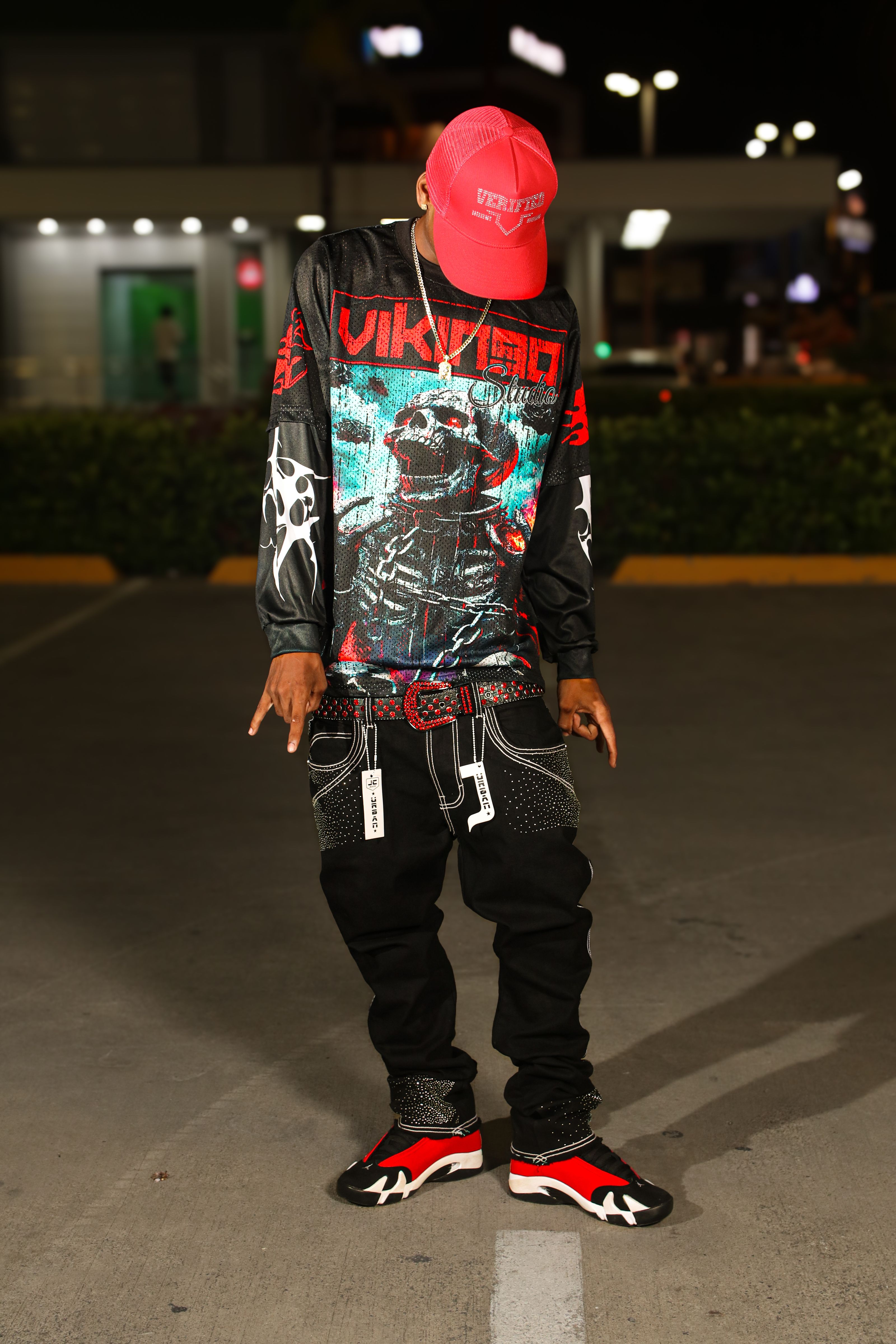 Um jovem exibindo moda urbana de rua à noite, com designs gráficos e acessórios ousados.