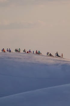 A group of tourists relishing the sunset on the dunes of Lençóis Maranhenses in Maranhão, Brazil.