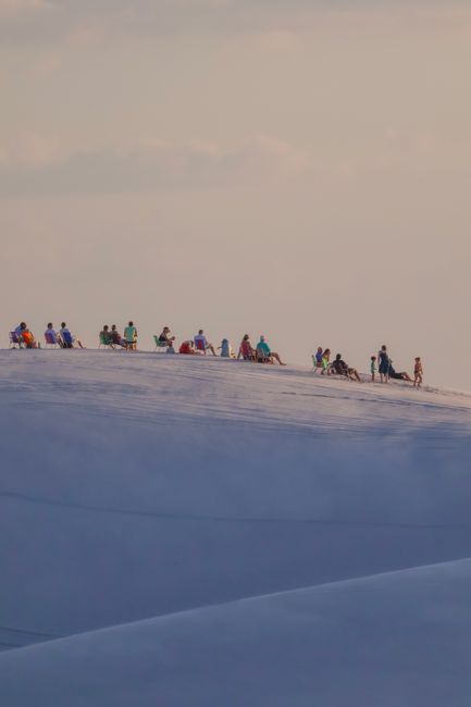 A group of tourists relishing the sunset on the dunes of Lençóis Maranhenses in Maranhão, Brazil.