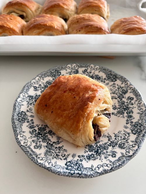 Free Freshly baked chocolate croissant on a decorative plate, showcasing rich, flaky pastry texture and enticing chocolate filling. Stock Photo