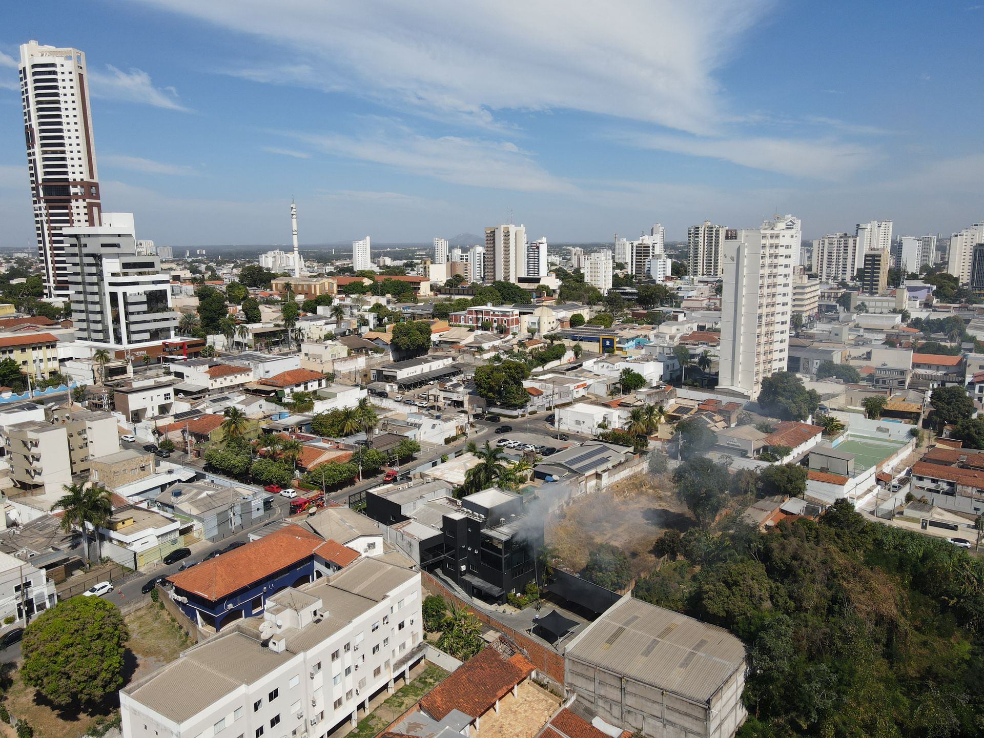 Aerial image capturing a small urban fire in Mato Grosso, highlighting cityscape and emergency response.