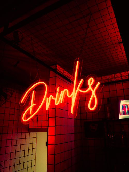 Free Neon sign reading 'Drinks' glowing in a dimly lit bar. Stock Photo
