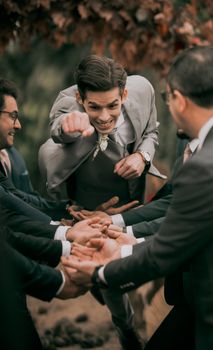 Groomsmen cheerfully lift the groom in a fun outdoor celebration, capturing the joyful wedding moment.