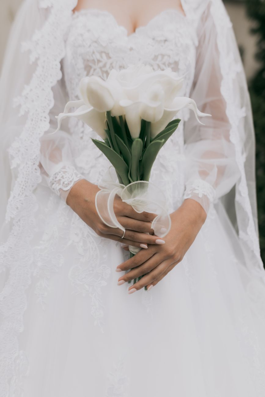 Bride in lace dress holding a white calla lilies bouquet. Perfect for wedding-themed photography.