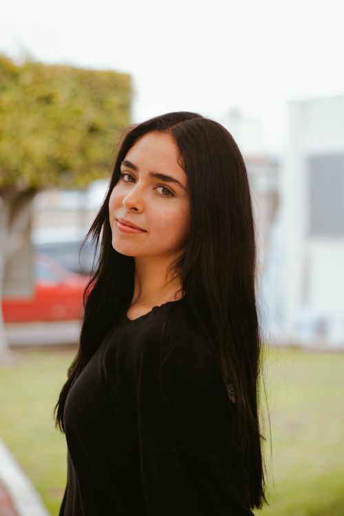 Free Close-up portrait of a young woman with long hair, standing outdoors. Stock Photo