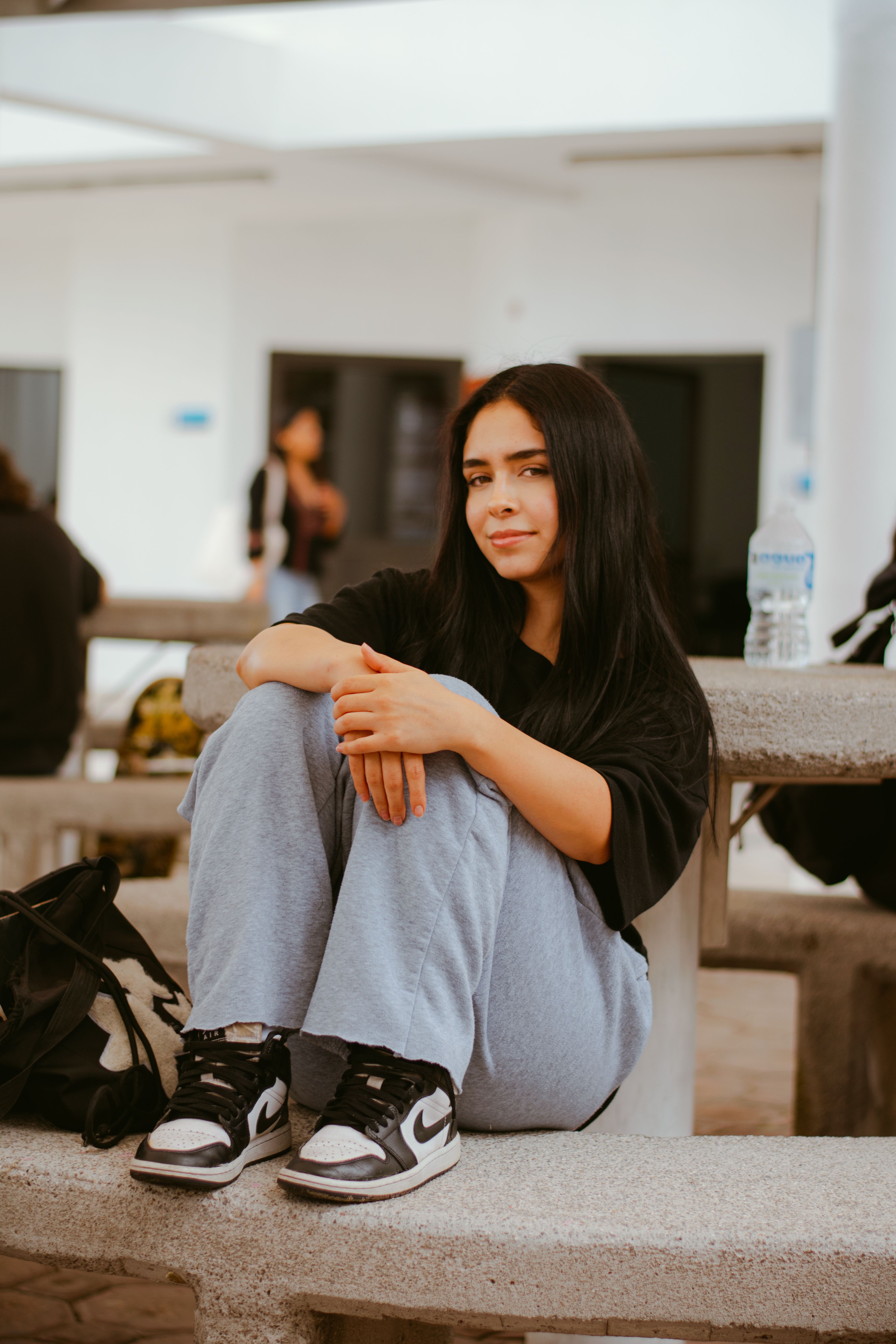 Teenager relaxing on a bench in comfortable clothing, outdoors, daytime.