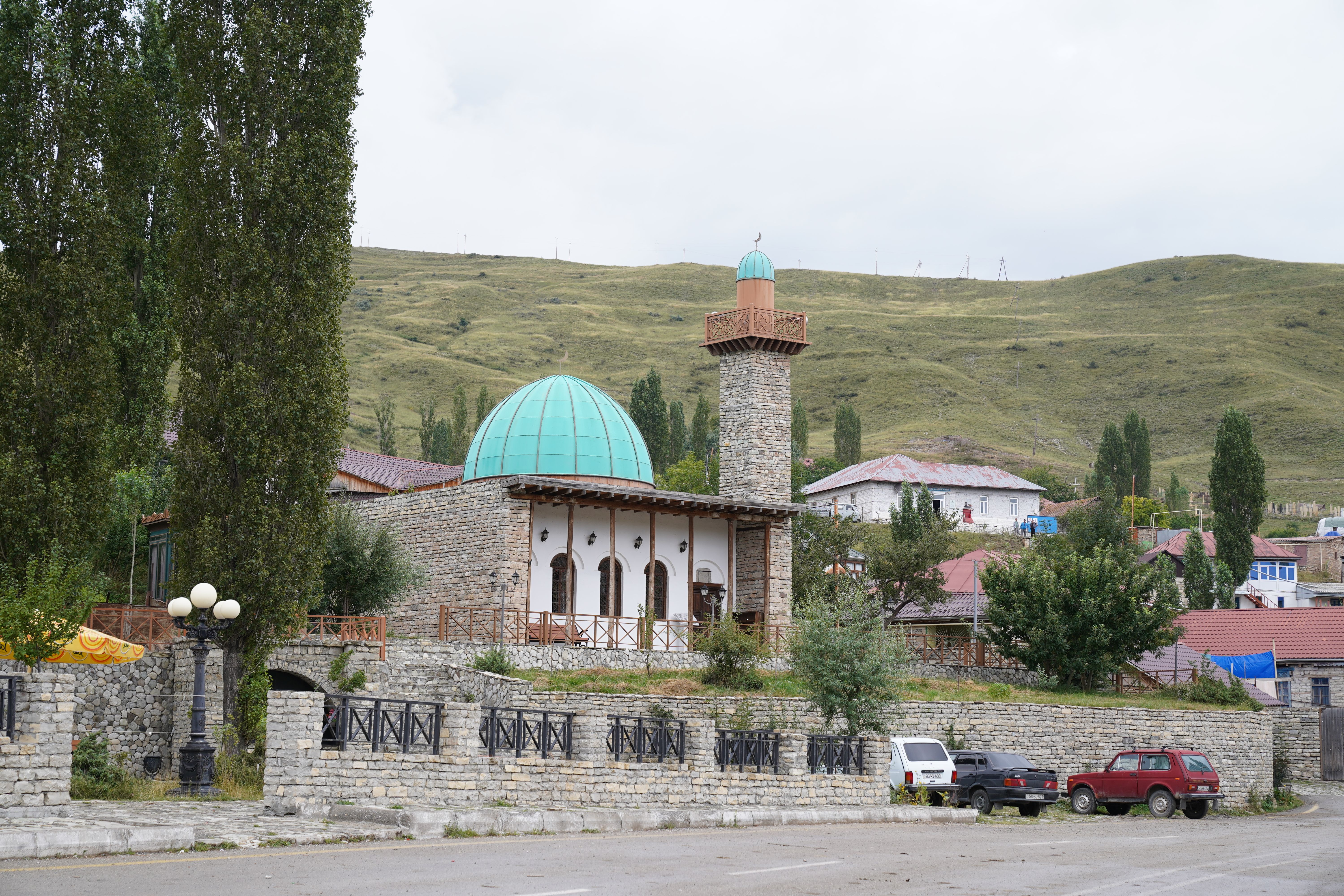 Beautiful mosque with green dome and minaret set in a serene rural landscape.