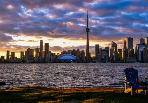 Dramatic sunset view of Toronto skyline featuring the iconic CN Tower across the water.