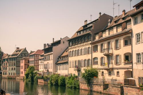 Free Quaint view of Strasbourg's half-timbered houses along a serene canal under a bright sky. Stock Photo