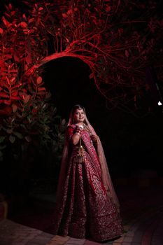 Stunning portrait of a bride in traditional red attire illuminated by warm lighting.
