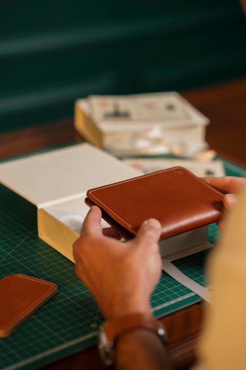Free Close-up of a person crafting a leather wallet in a well-organized workspace. Stock Photo