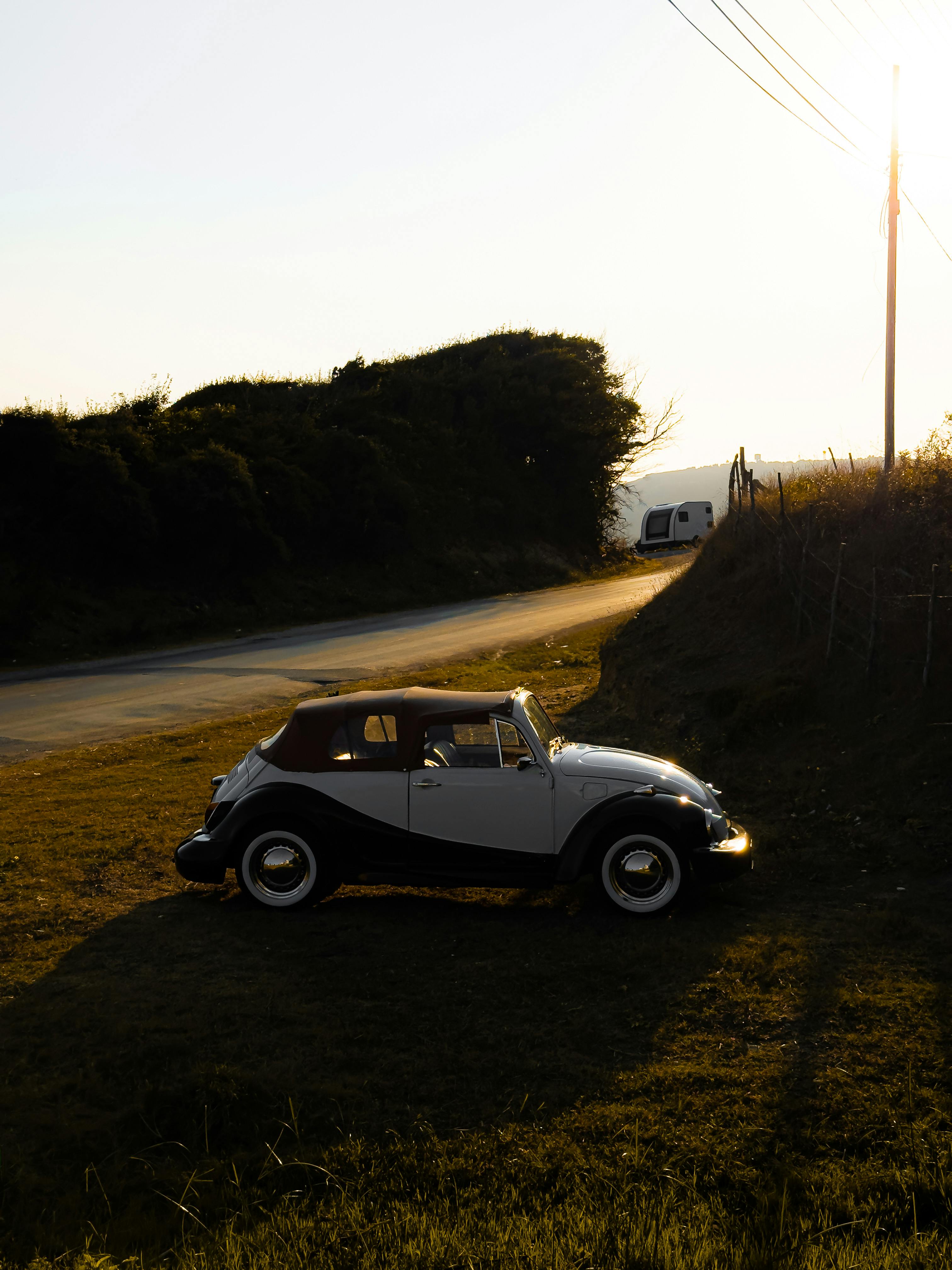 Free A classic vintage car parked on a country road during sunset. Stock Photo
