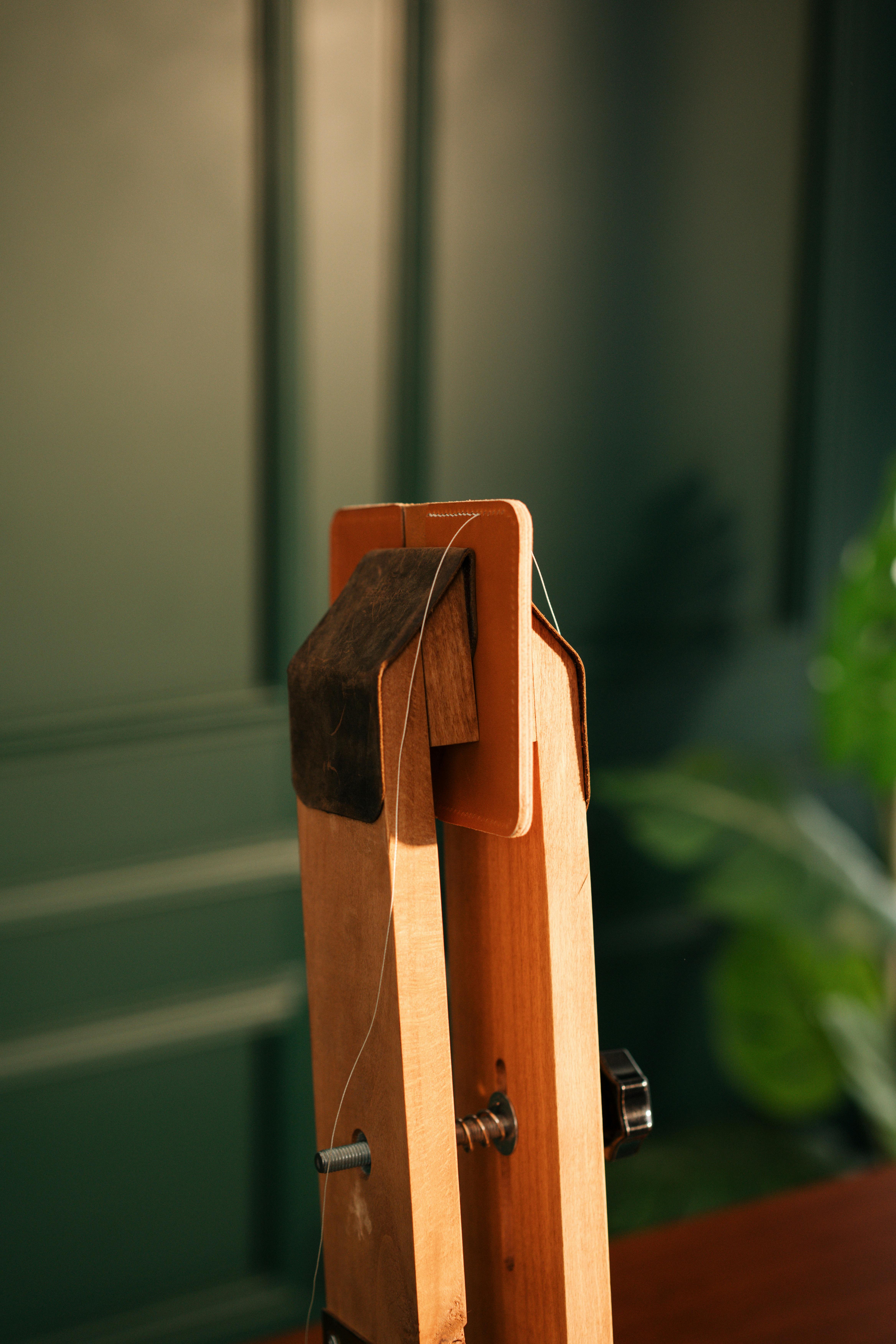 gratis Artistieke close-up van een vintage houten gereedschap met draad, tegen een groene muurachtergrond. Stockfoto