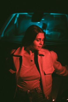 A woman in moody night lighting with red and blue hues, in Mortagne-du-Nord, France.