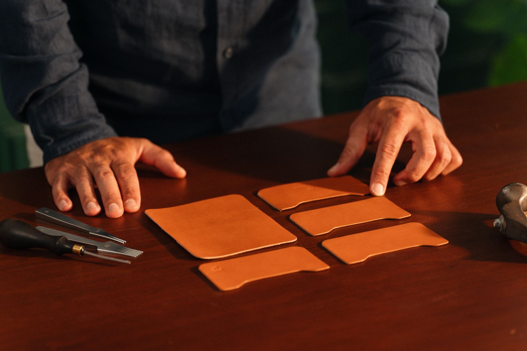 Hands of a craftsman arranging cut leather panels on a workbench — photo by G&uuml;l Işık on Pexels