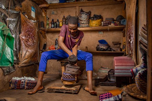 Nigerian artisan skillfully crafting shoes in a traditional workshop in Kano, Nigeria.