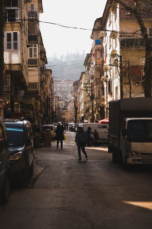 Free A busy urban street scene with pedestrians and cars under warm afternoon lighting, capturing city life. Stock Photo