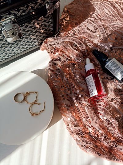 Flat lay of beauty serums and jewellery on sand — photo by elena_ sher on Pexels