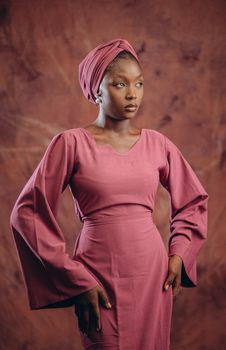 Elegant portrait of a woman in pink traditional attire with matching headwrap, classic style.