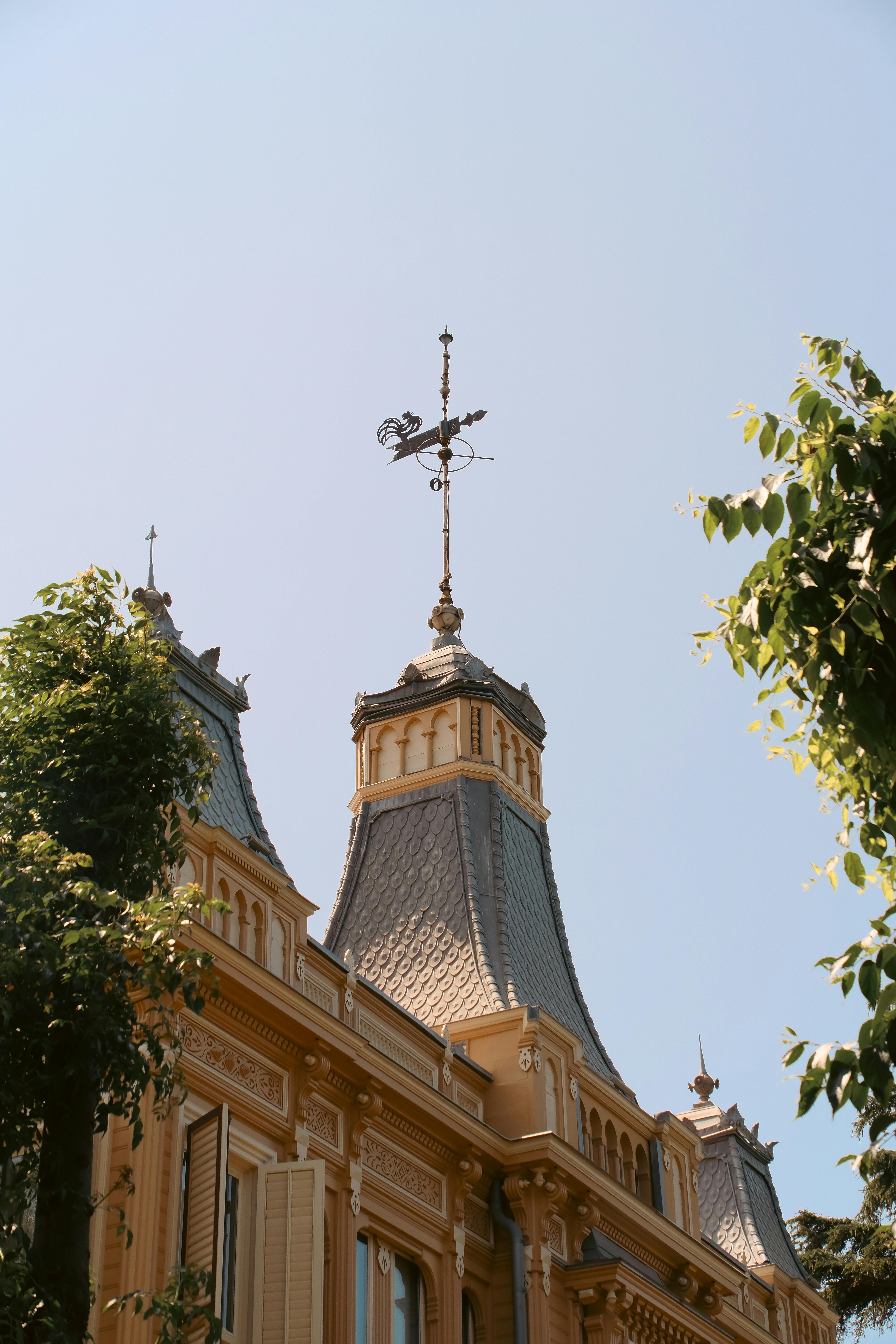 Charming historic building with vintage roof and a decorative weather vane in a clear sky.