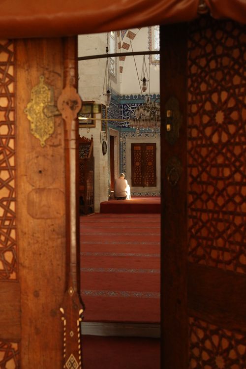 Free A person in prayer inside a historic mosque with ornate decorations. Stock Photo