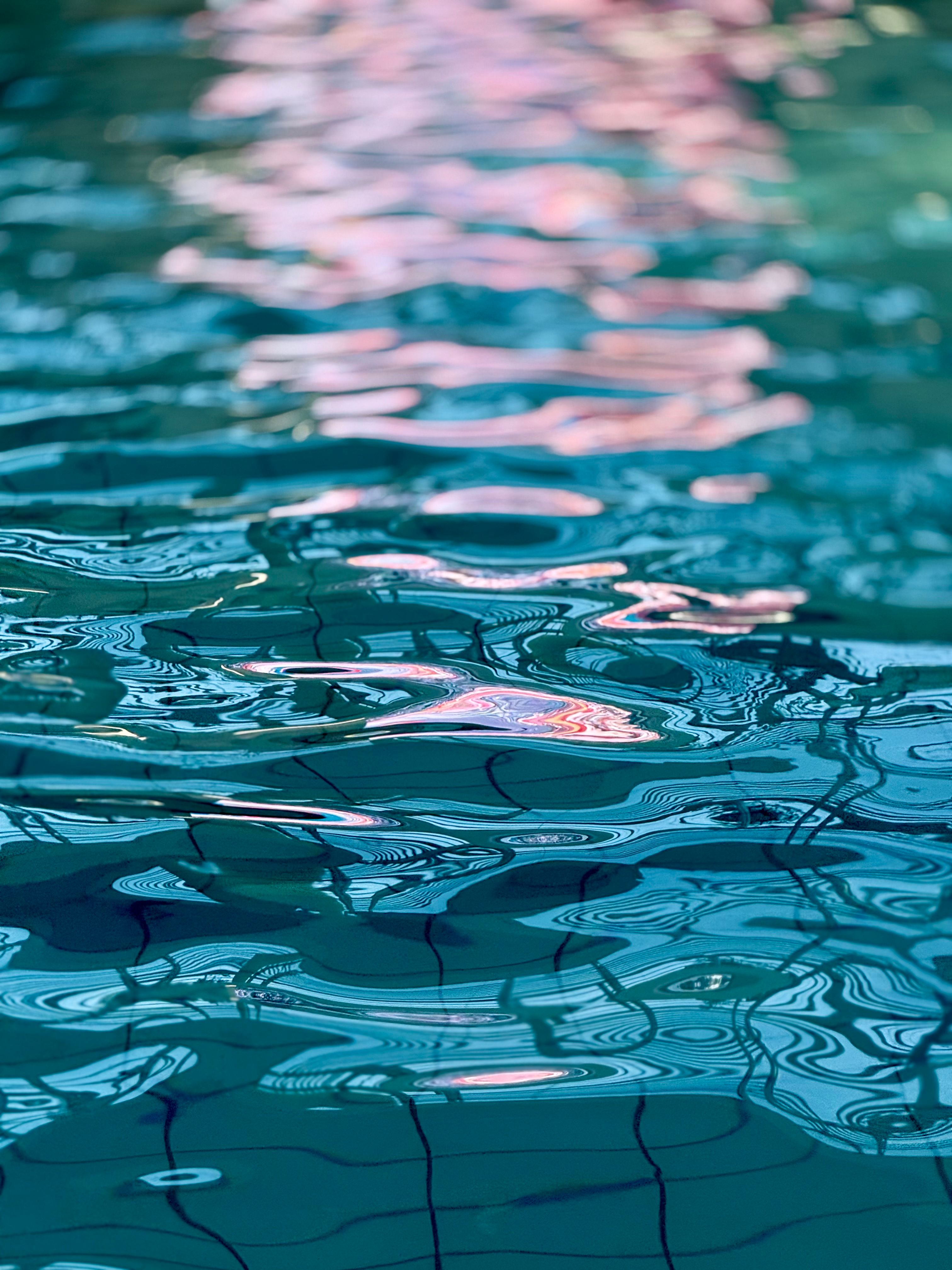 Colorful reflections on a swimming pool surface with blue and pink hues.