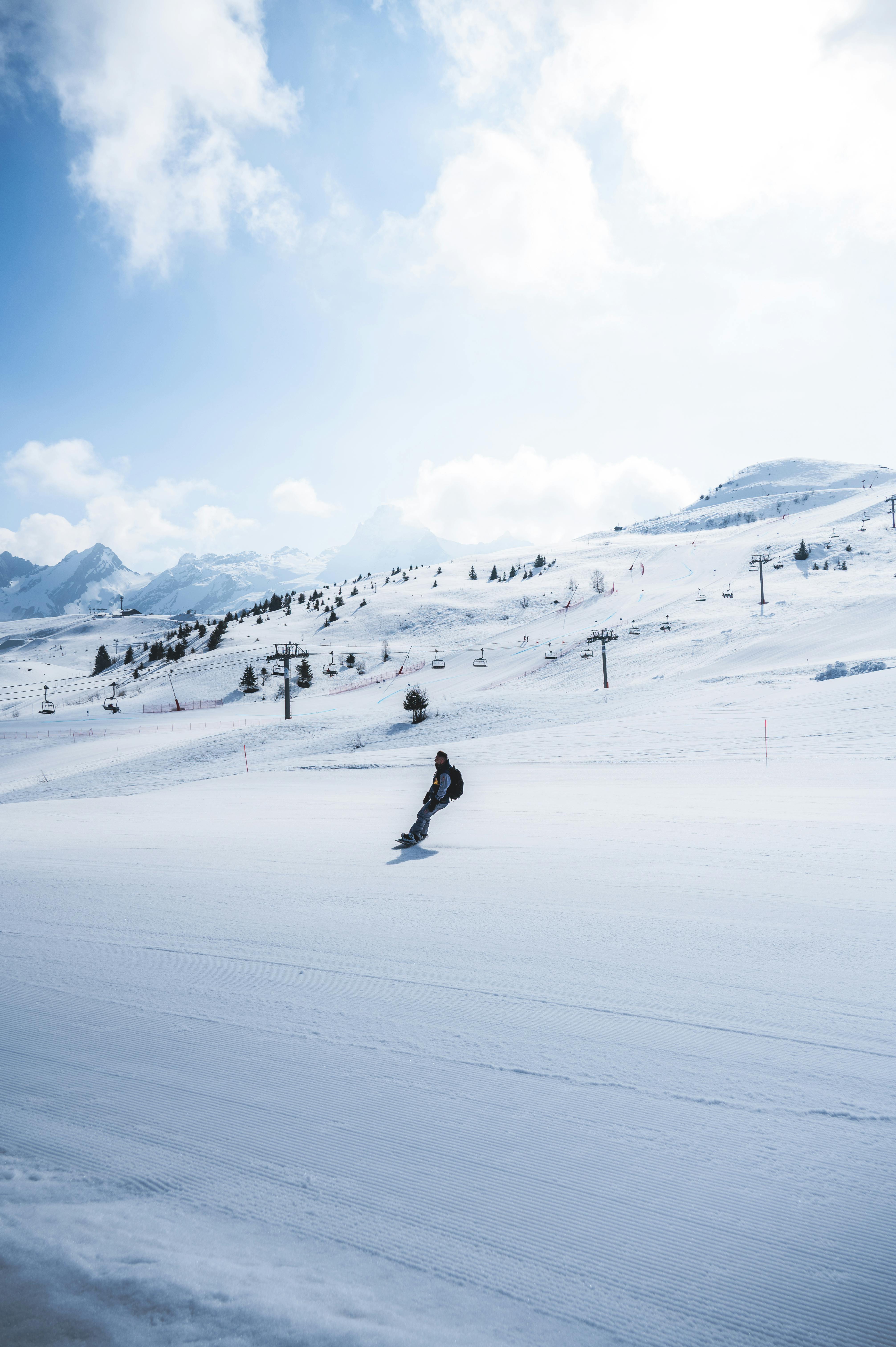 A lone snowboarder gracefully glides down a snow-covered mountain on a clear day.