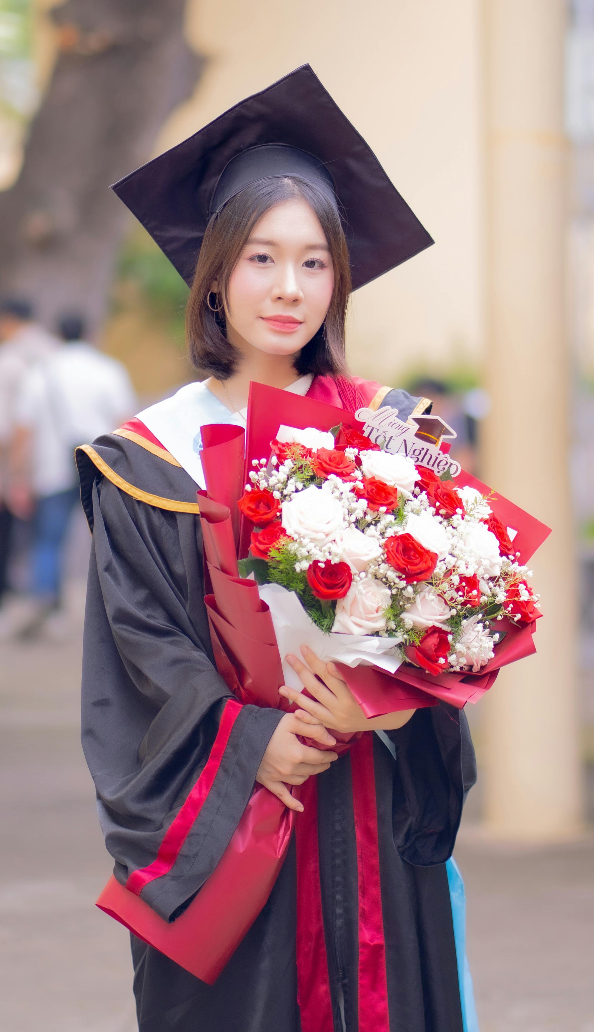 Young graduate holding a bouquet of flowers on graduation day.