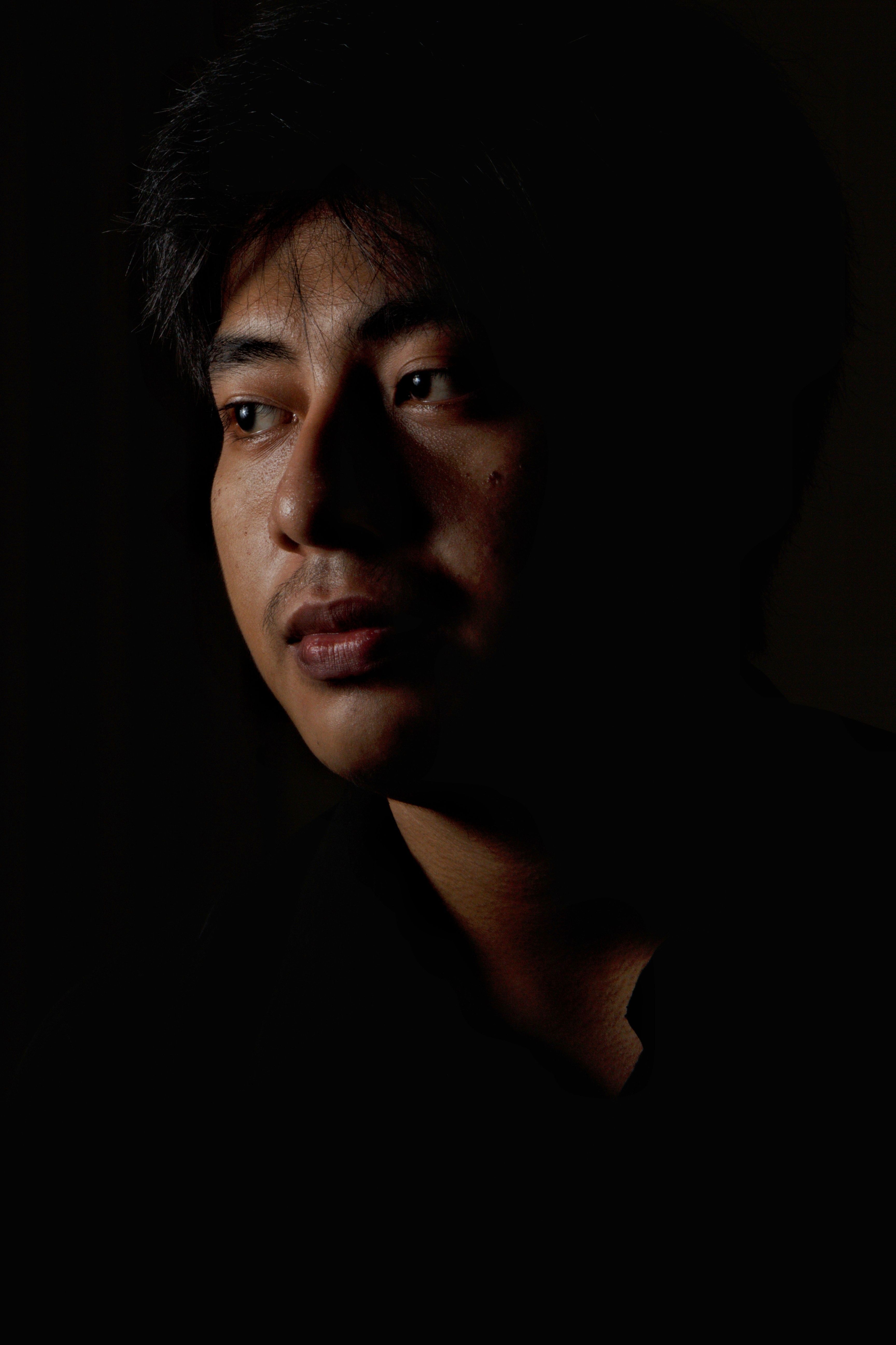 Moody portrait of a young man looking into distance, emphasizing deep introspection.
