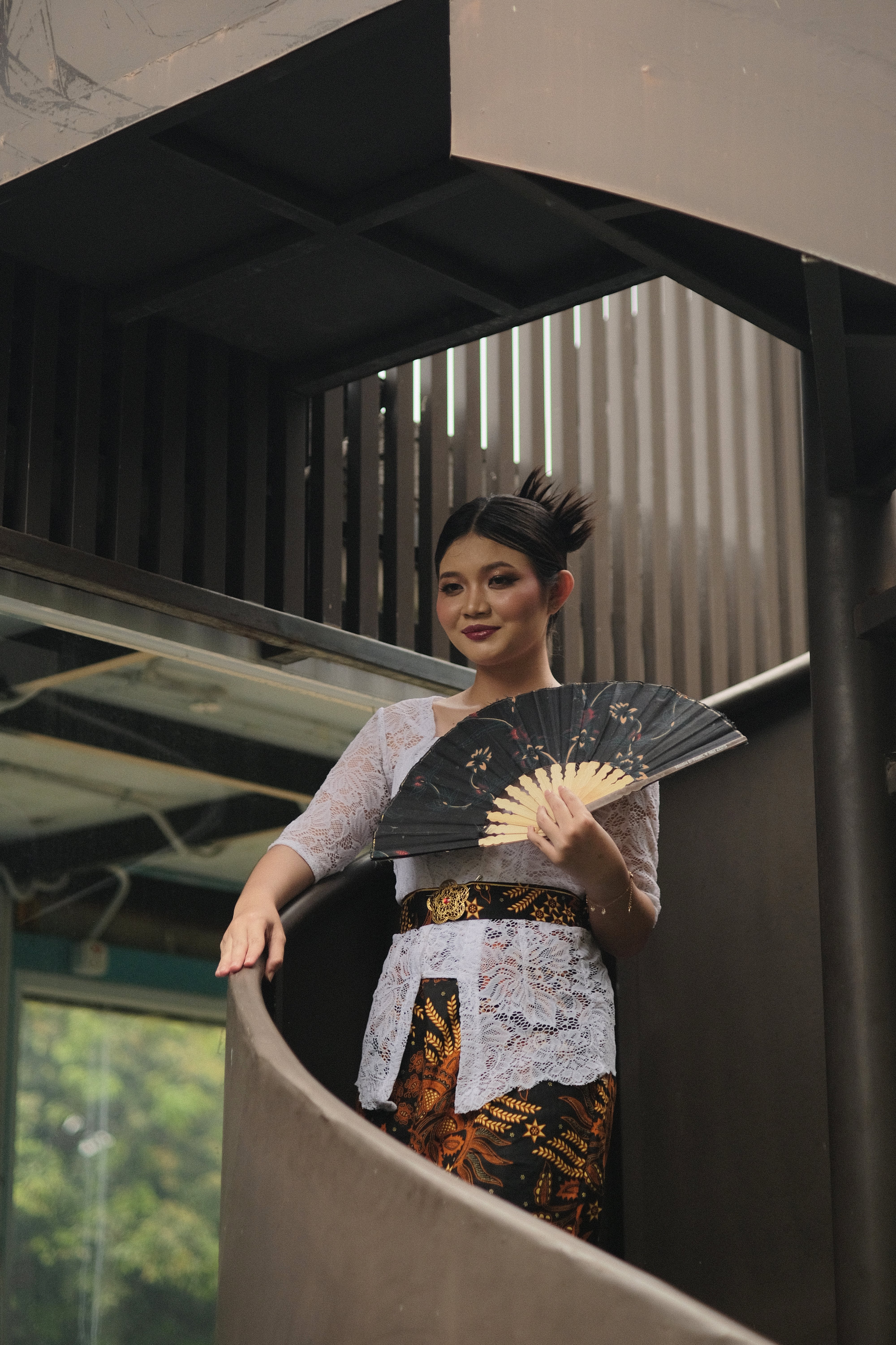 Portrait of a woman in traditional Indonesian attire holding a fan, taken in Jakarta.