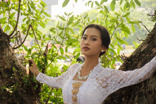 Free Portrait of a young woman in traditional Indonesian attire in a lush outdoor setting. Stock Photo