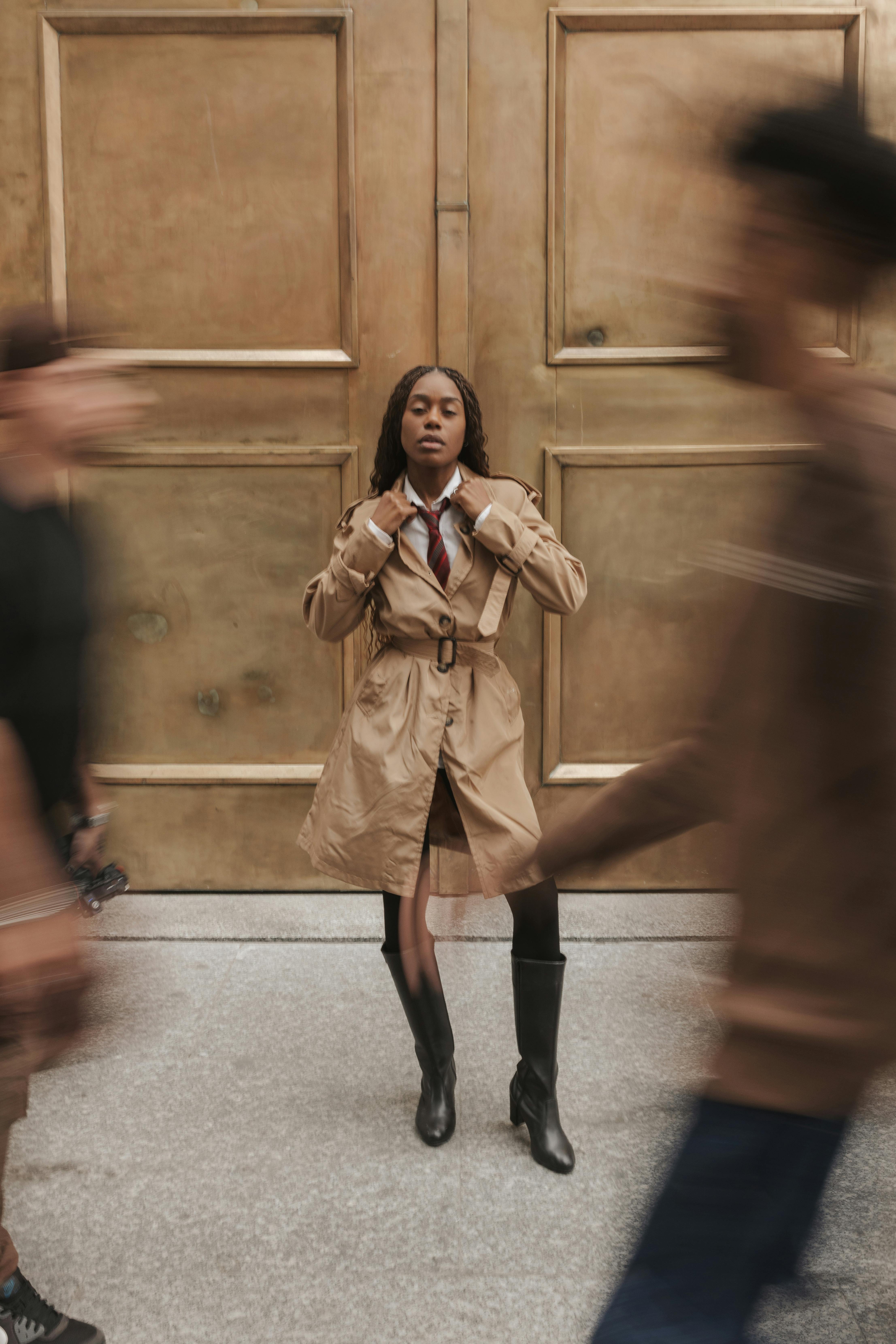 Gratis Una donna con un elegante trench si erge in mezzo alla folla in movimento, creando una scena urbana dinamica. Foto a disposizione