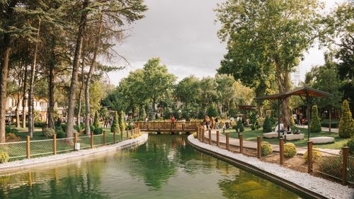 Free Peaceful park scene featuring a serene pond, a wooden bridge, and lush greenery. Stock Photo