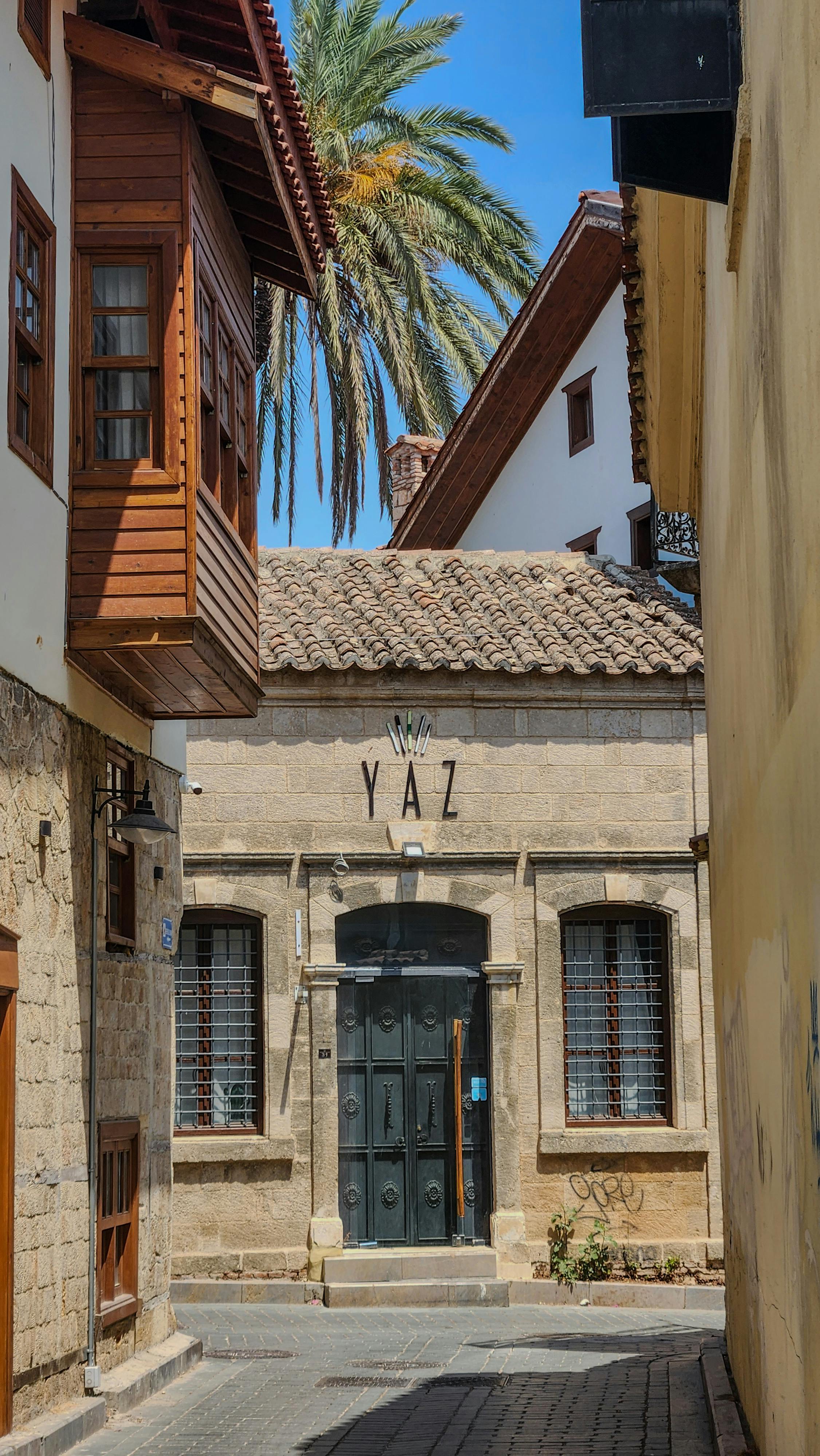 Explore a picturesque alleyway featuring historic stone buildings with wooden accents under a bright blue sky.