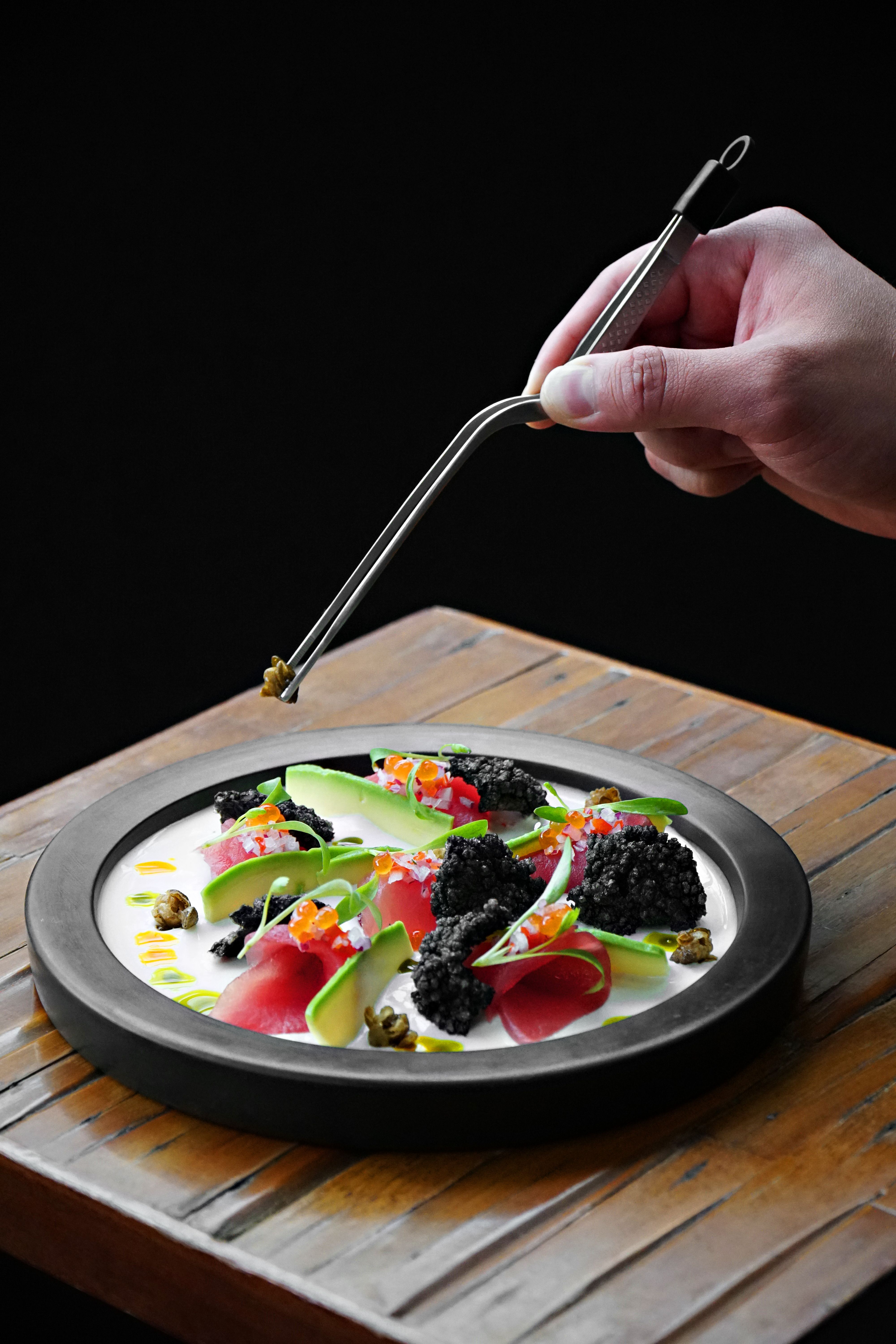 Elegant gourmet dish with black caviar, vegetables, and edible flowers in Lima, Peru.