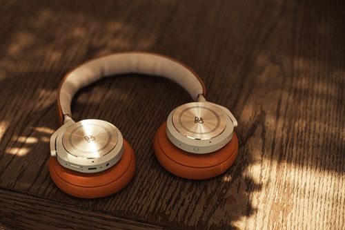 Free Stylish wireless headphones with orange cushions on a wooden surface, lit by natural light. Stock Photo