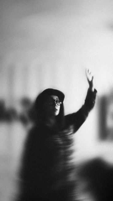 Blurred monochrome portrait of a woman with raised arm, creating an abstract effect.