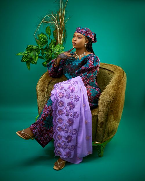Free Confident woman sitting in colorful traditional African dress on vintage chair. Stock Photo