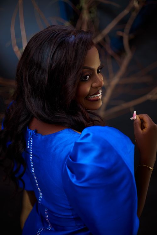 Free Portrait of a woman in a vibrant blue dress, smiling with a captivating gaze. Stock Photo