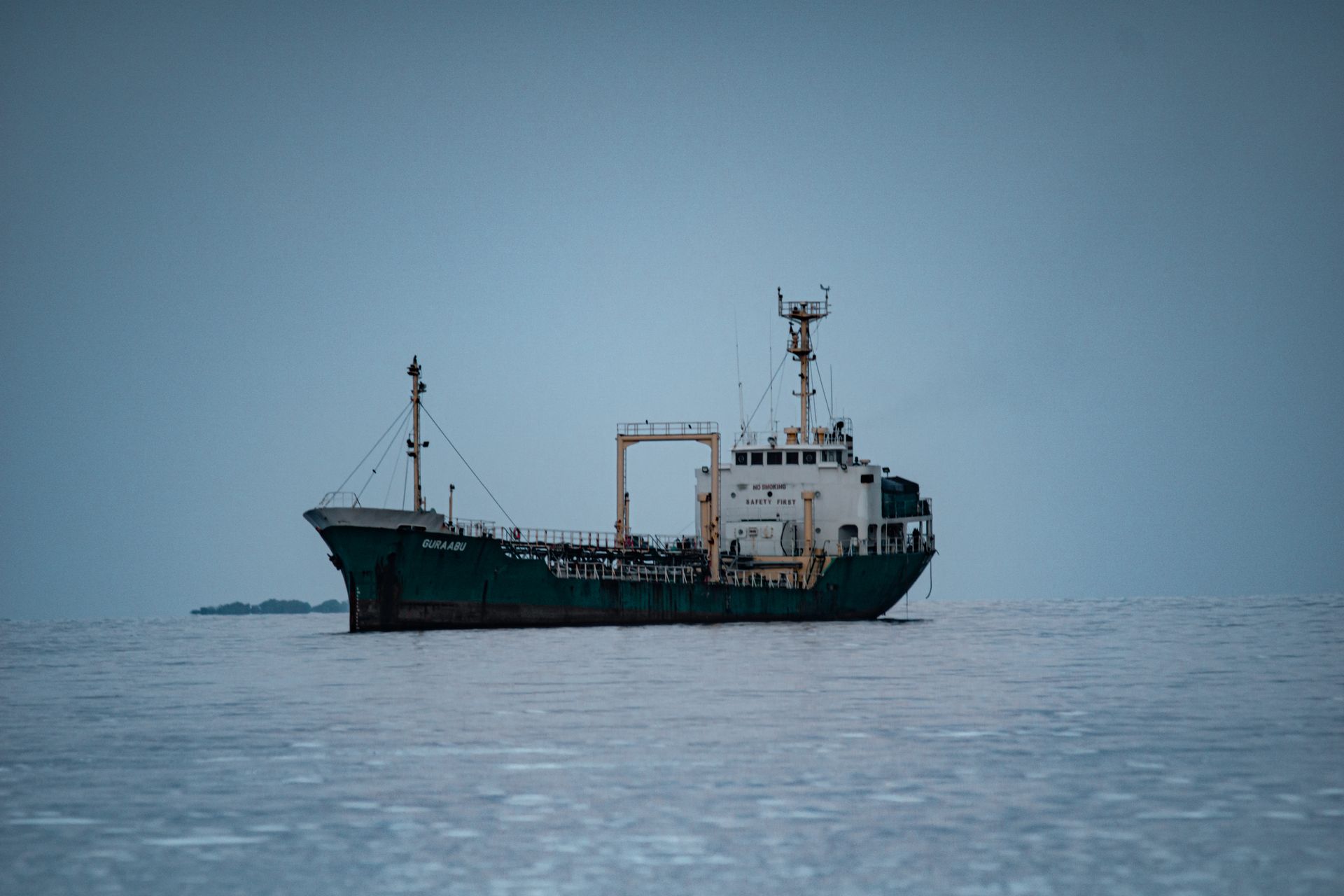 Un buque de carga anclado en un mar gris y nublado, que evoca una tensa espera marítima.