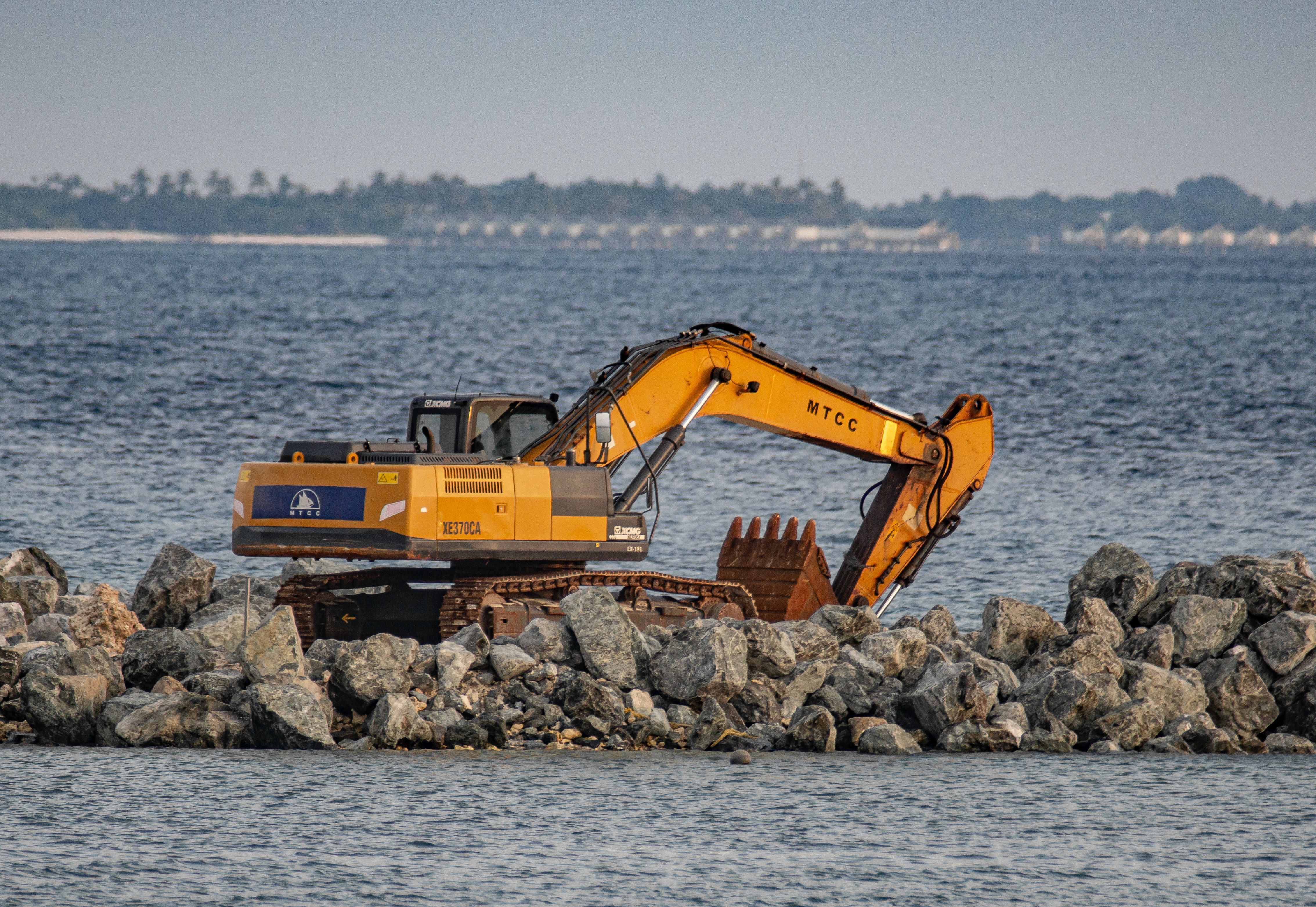 Excavator on Rocky Shoreline Engaged in Coastal Construction · Free ...