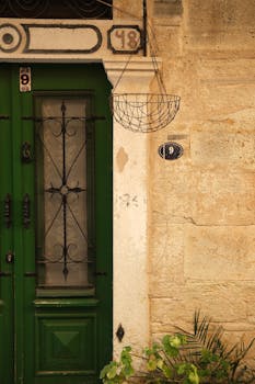 Historic stone facade with green door and metal basket in İzmir, Turkey.