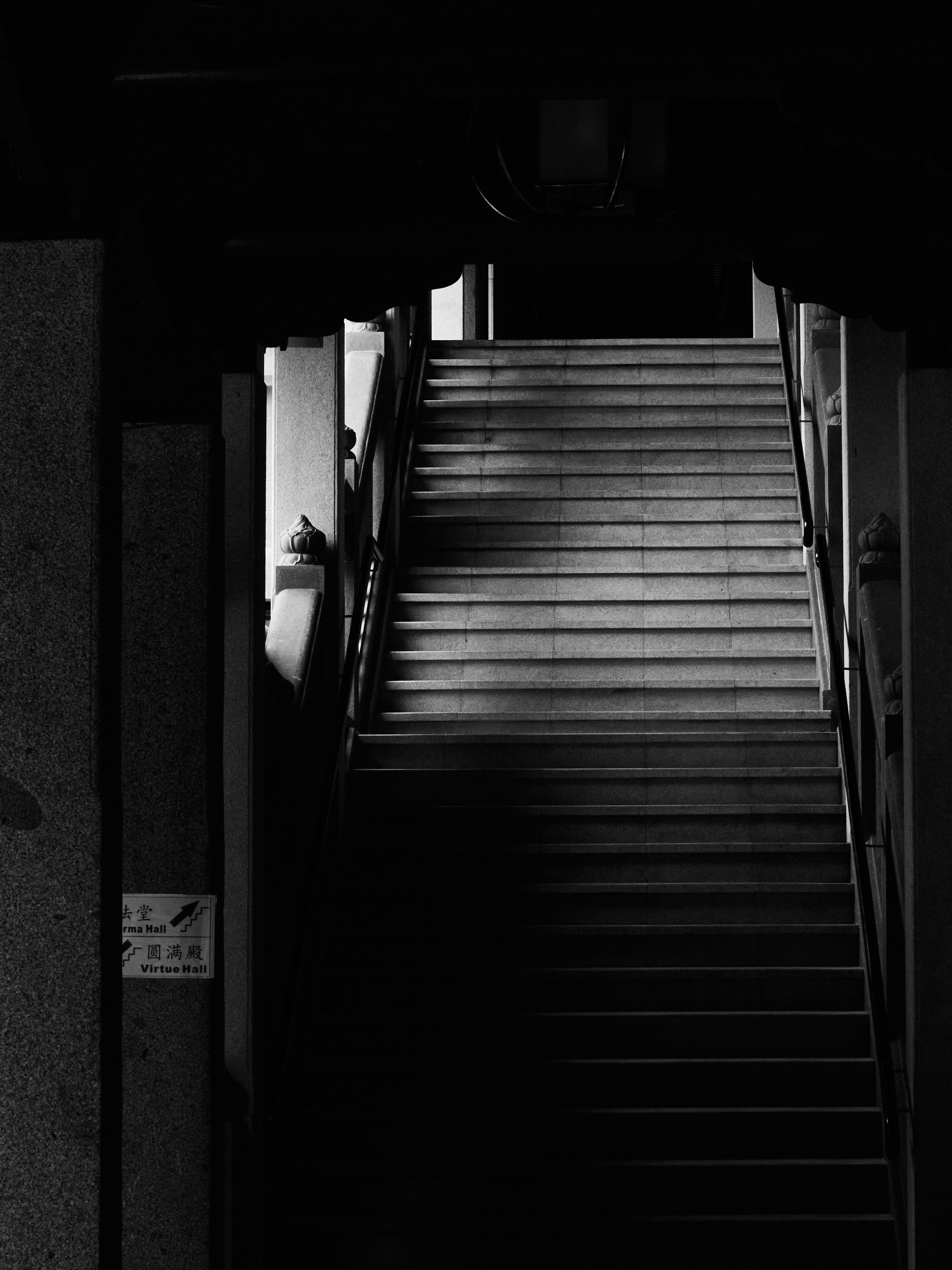 Free Atmospheric black and white photo of a staircase with dramatic lighting and shadows. Stock Photo