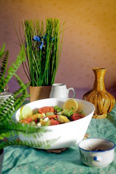 A vibrant fresh salad in a white bowl surrounded by tropical home decor elements.