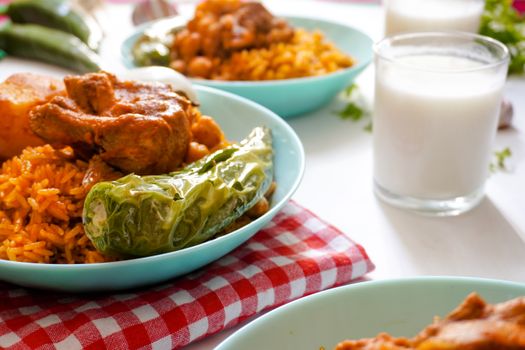 A vibrant dish of spicy rice, chicken, and green peppers served with milk on a checkered cloth.