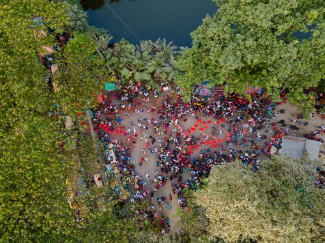 Aerial view of a lively outdoor festival surrounded by lush greenery and a waterbody.