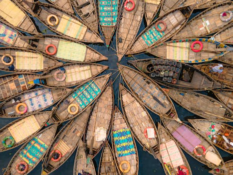 Vibrant top-down view of wooden boats with colorful patterns docked on a river.