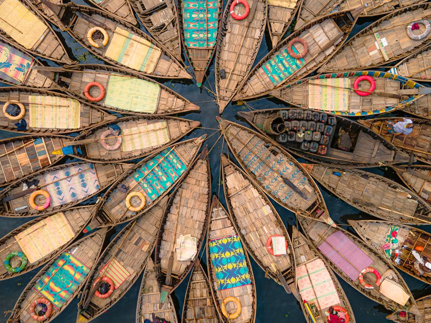 Vibrant top-down view of wooden boats with colorful patterns docked on a river.
