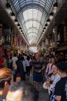 Tokyo'da kemerli bir çatının altında çeşitli alışveriş yapanların bulunduğu kalabalık alışveriş caddesi.